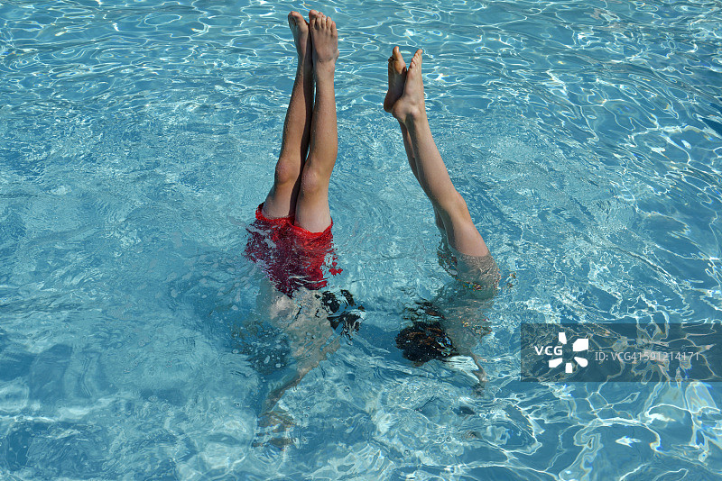 青少年男女在游泳池里倒立图片素材