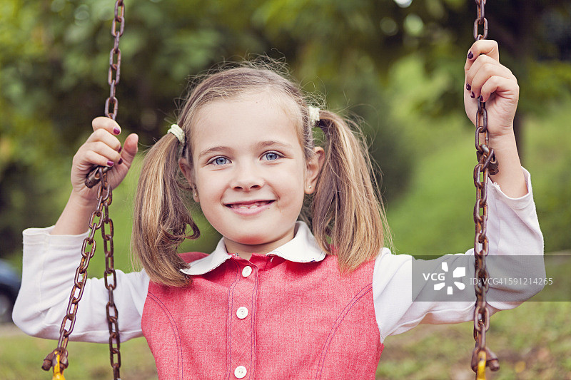 在秋千上微笑的辫子小女孩肖像图片素材