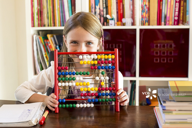 微笑的小女孩坐在算盘后面图片素材