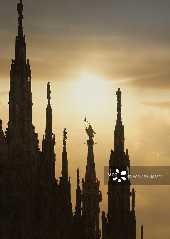 米兰大教堂最高尖顶上的圣母雕像日落剪影(la Madonnina),意大利图片素材