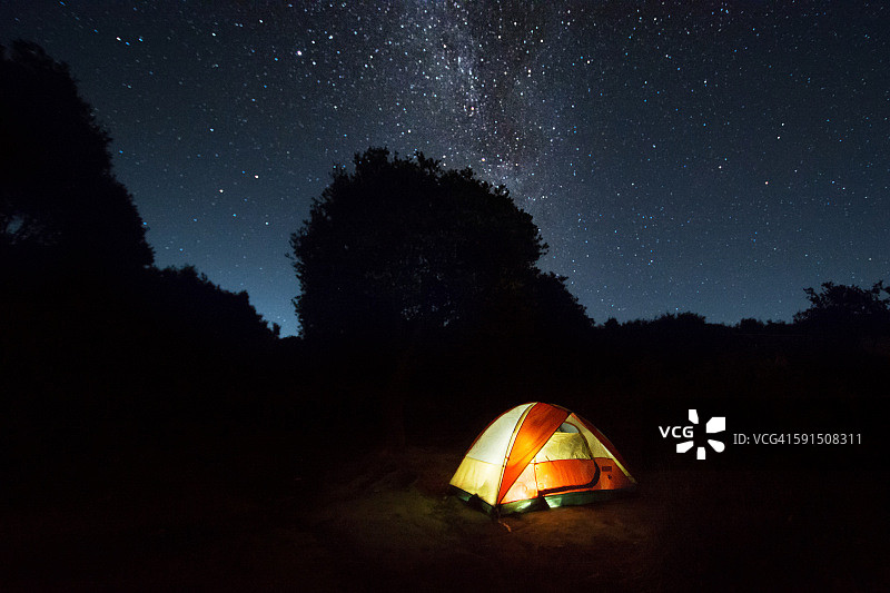 星夜下黑暗中亮着灯的孤独帐篷图片素材