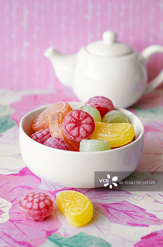 粉色背景上的彩色糖果碗和茶壶图片素材