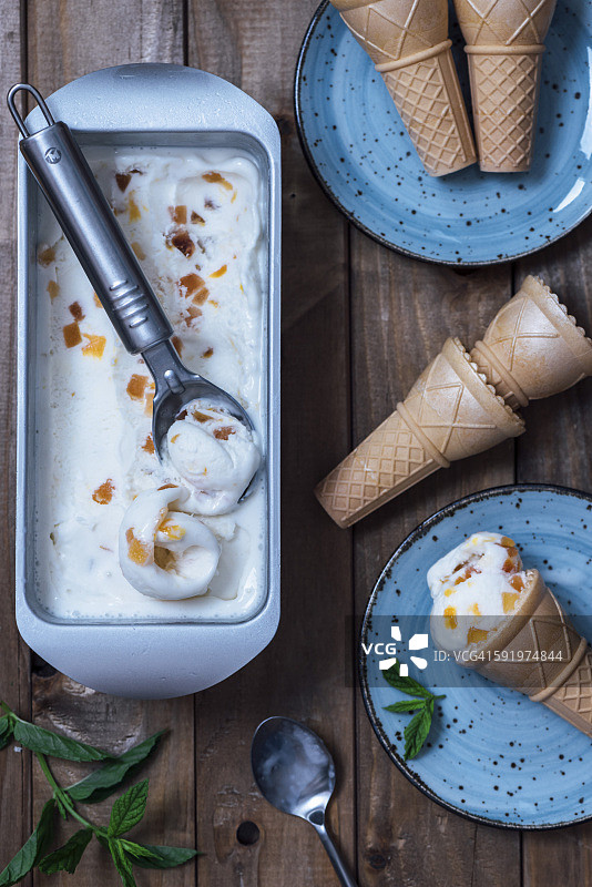 平底锅里的桃子冰淇淋和两个蓝色盘子上的冰淇淋甜筒图片素材