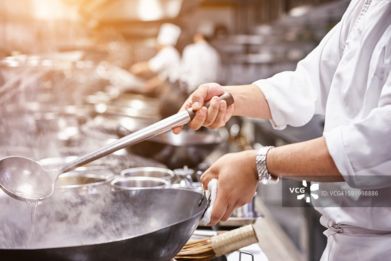 厨师在餐厅厨房的炉子旁用平底锅图片素材