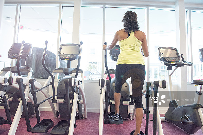 健身房中年妇女使用踏步机背影图片素材