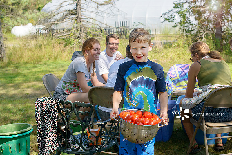 一家人拿着漏勺里的西红柿看着镜头微笑图片素材