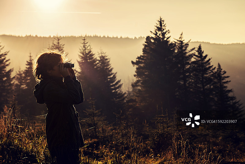 男孩使用双筒望远镜观看图片素材