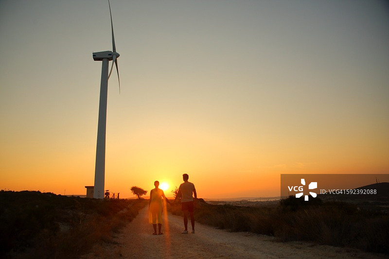 情侣手牵手在风力涡轮机旁图片素材