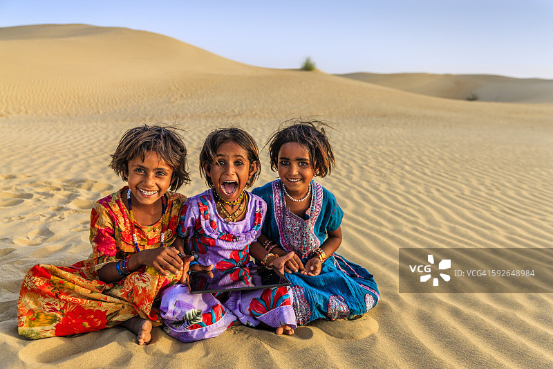 快乐的印度小女孩在印度沙漠村庄使用平板电脑图片素材