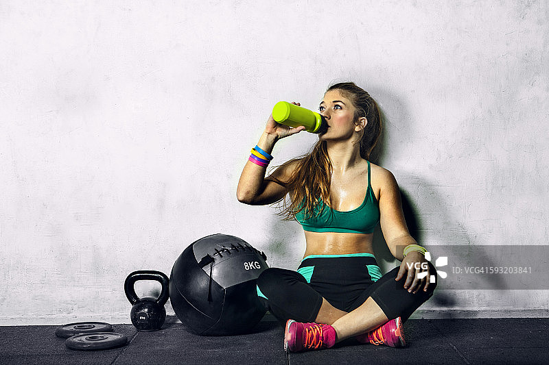 年轻女人在健身房休息和喝水图片素材