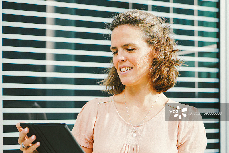 在城市景观中使用平板电脑的成功女商人肖像图片素材