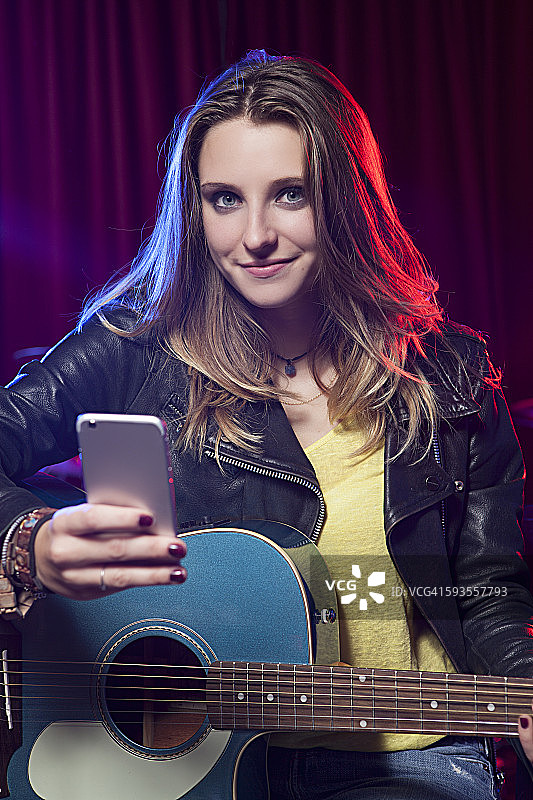 抱着吉他和智能手机的女孩图片素材