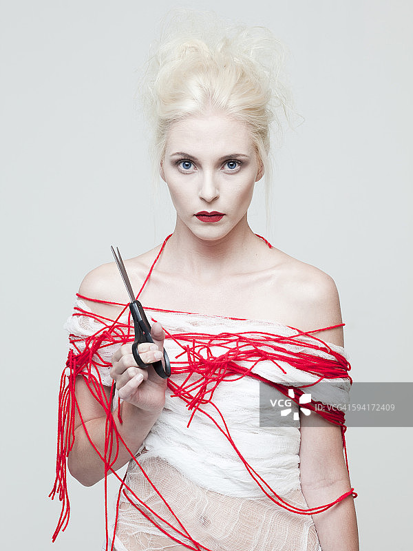 年轻女子被红色丝线缠绕的棚拍肖像图片素材