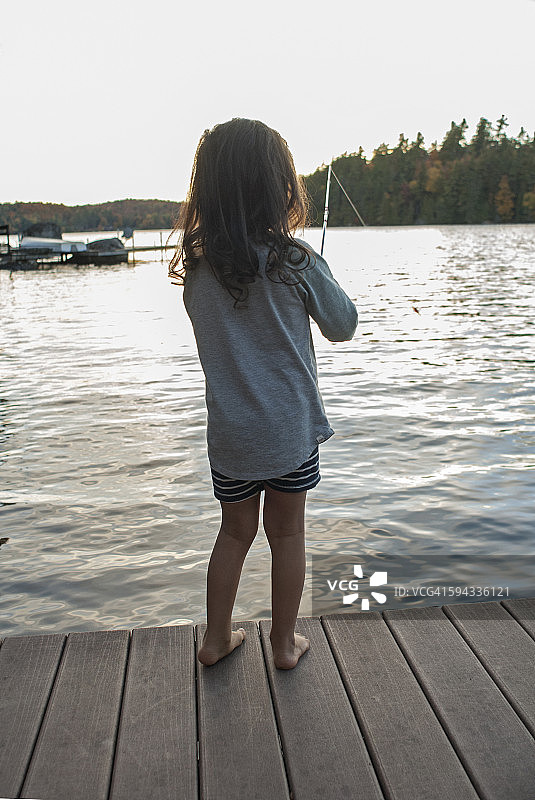 儿童在湖上木制码头钓鱼图片素材