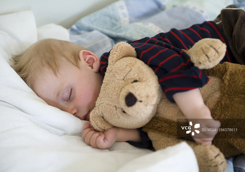 男孩抱着泰迪熊睡觉图片素材