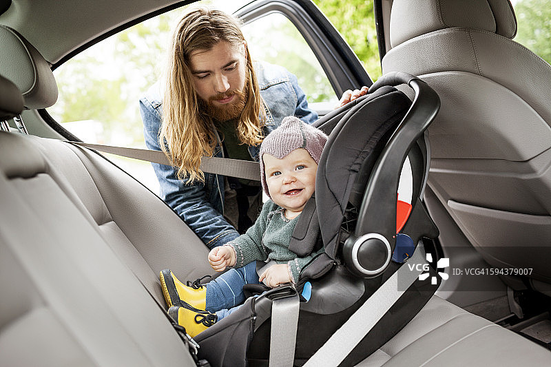 父亲将婴儿放入汽车安全座椅图片素材