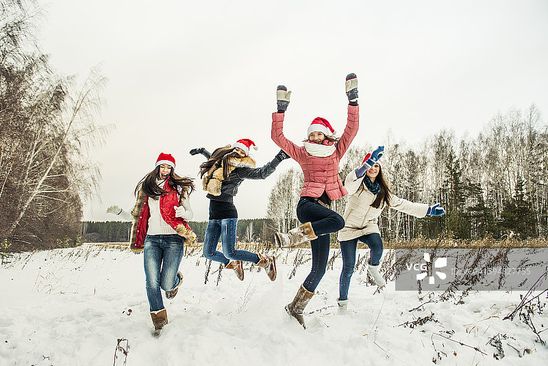 在雪地里高兴跳跃的白人女孩们图片素材
