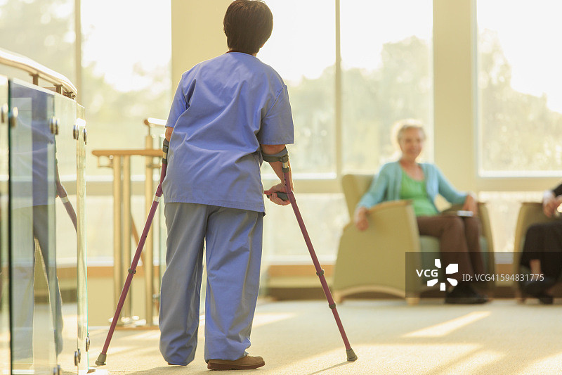 患有脑瘫的护士拄着拐杖走在诊所的走廊里图片素材