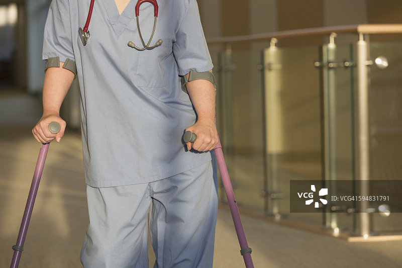 患有脑瘫的护士拄着拐杖走在诊所的走廊里图片素材