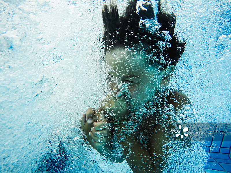 男孩捏着鼻子跳入游泳池图片素材
