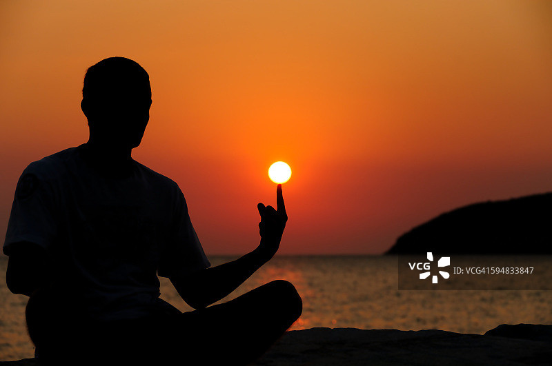 男人剪影，用手指托起太阳图片素材