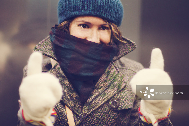 穿着暖和的女人竖起两个大拇指图片素材