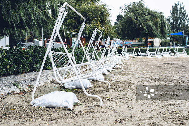 寒冷夏日空旷海滩上的秋千长椅图片素材