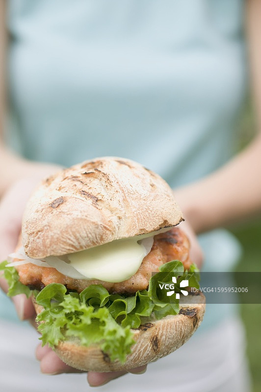手持鸡肉汉堡的女人图片素材