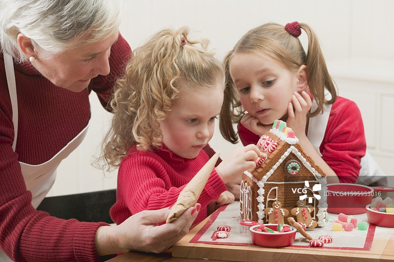 小女孩和奶奶装饰姜饼屋图片素材