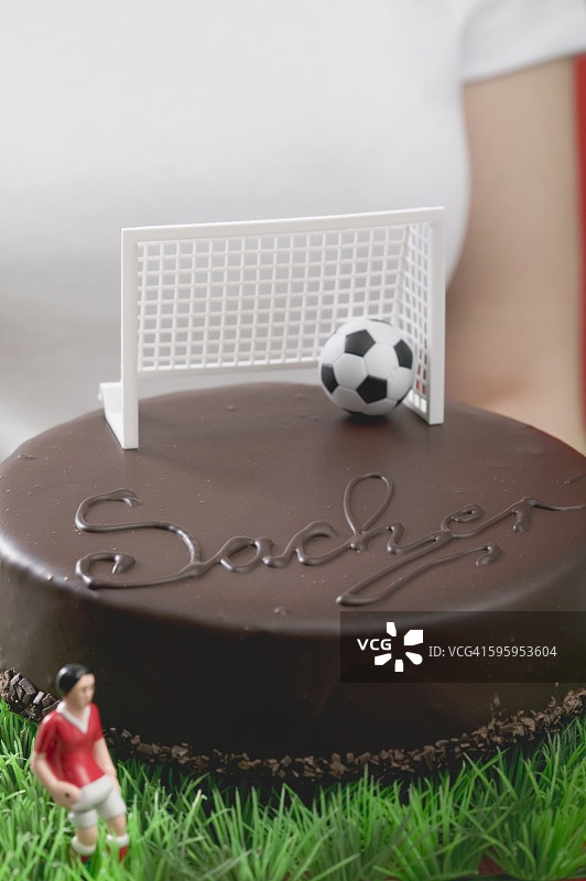 女人拿着带有足球人偶和足球的萨赫蛋糕图片素材