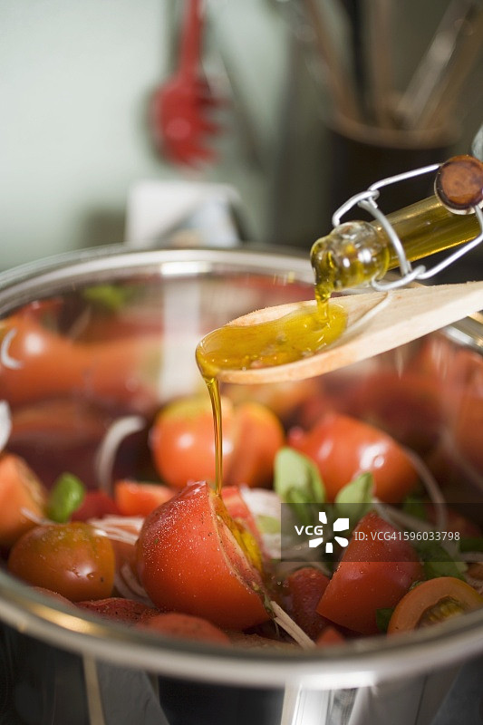 往番茄沙拉上倒橄榄油图片素材