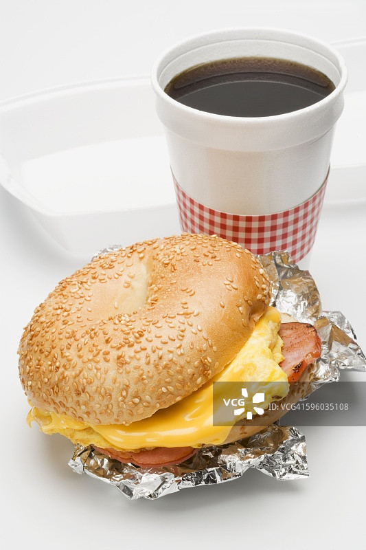 芝麻百吉饼里的炒鸡蛋和火腿，一杯咖啡图片素材