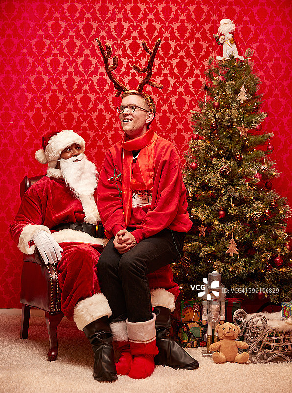 长着鹿角的男孩坐在圣诞老人的腿上图片素材