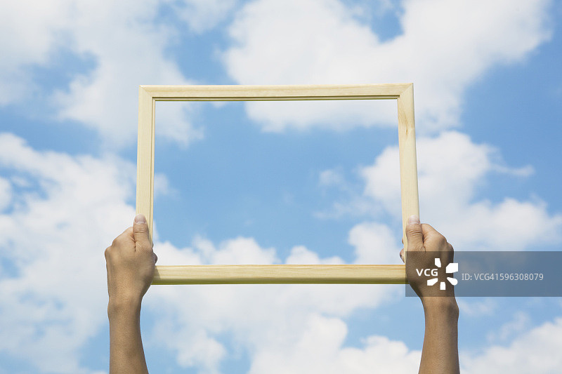 手持天空背景的画框图片素材
