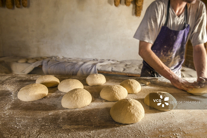年轻面包师揉捏有机面团图片素材