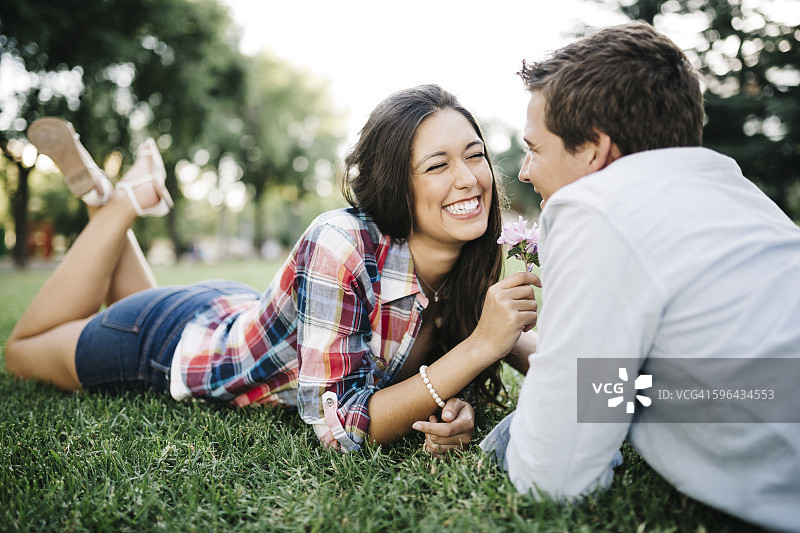 年轻情侣躺在公园的草地上图片素材