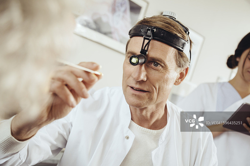 戴着手术头灯检查病人的医生图片素材