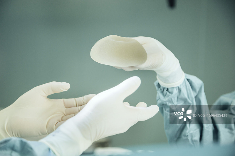手术室护士在手术中将硅胶植入物递给外科医生图片素材