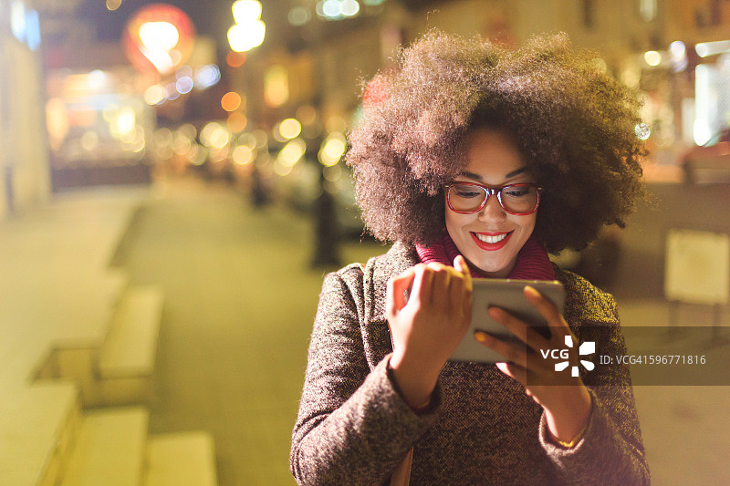 美丽的非洲年轻女人在夜晚使用平板电脑图片素材