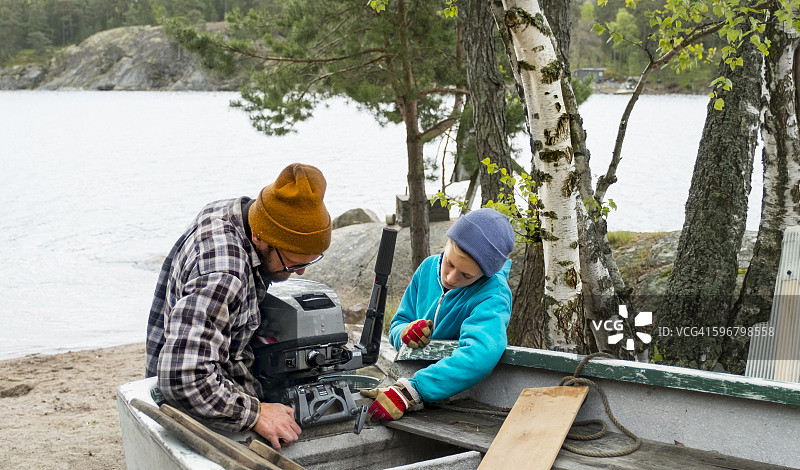 父子俩在船下水前修理发动机图片素材