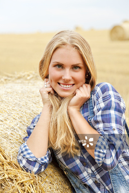 笑容甜美的年轻农民在草垛后图片素材