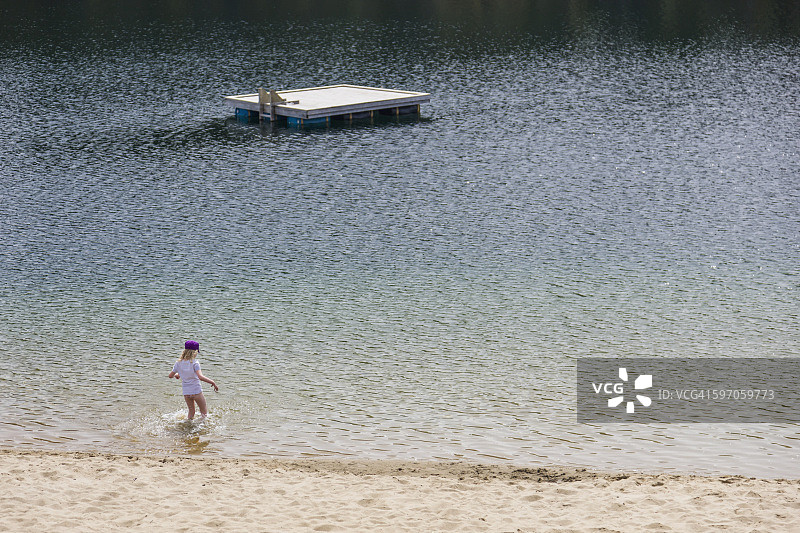 在加拿大育空地区幸运湖的沙滩上玩耍的年轻女孩图片素材