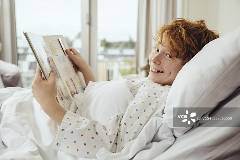 生病男孩在医院病床上读书图片素材