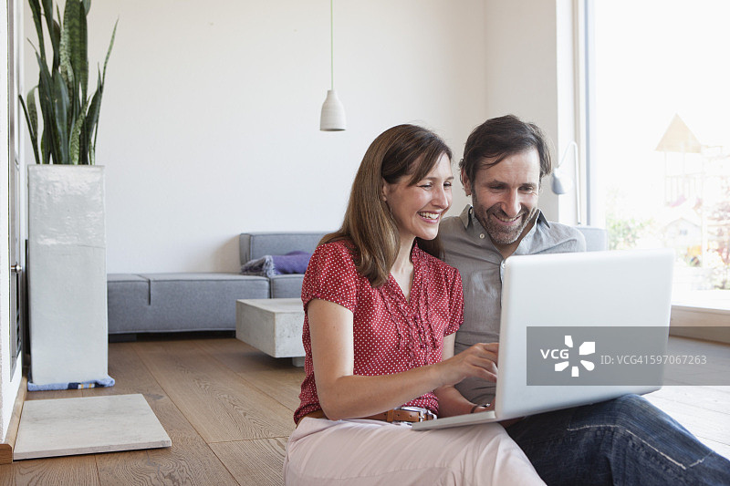 中年夫妇坐在地板上使用笔记本电脑图片素材