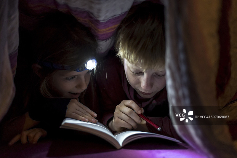 兄妹在毯子下看书图片素材