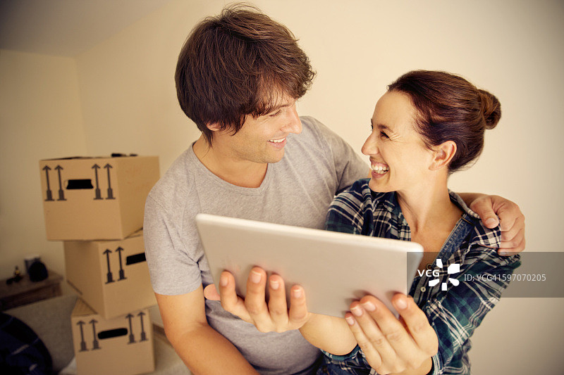 在纸箱背景下手持平板电脑的幸福情侣图片素材