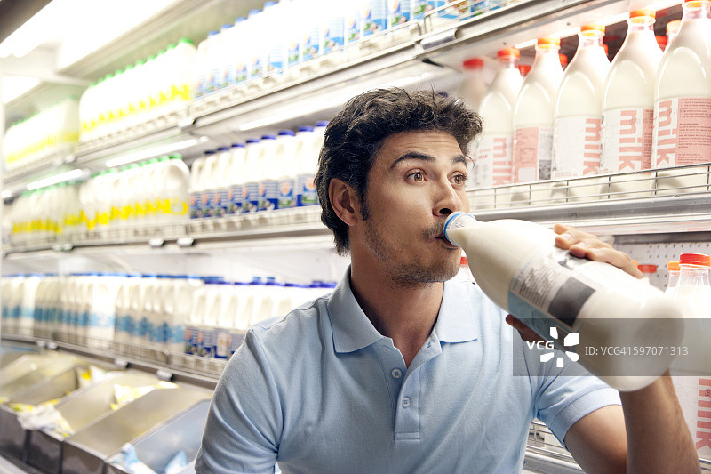 男人在超市冰箱前喝牛奶图片素材