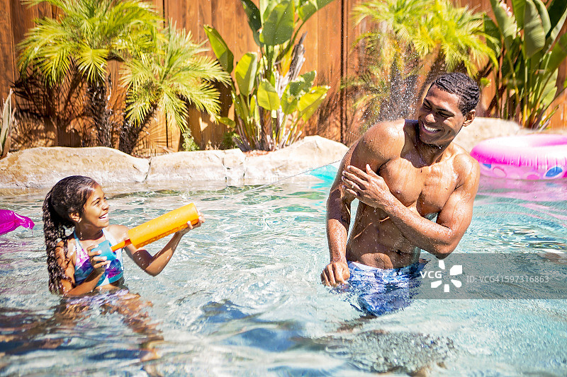 父女在游泳池里玩水枪图片素材