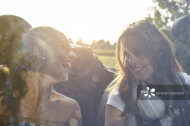 两位年轻女性朋友在敞篷车里聊天图片素材