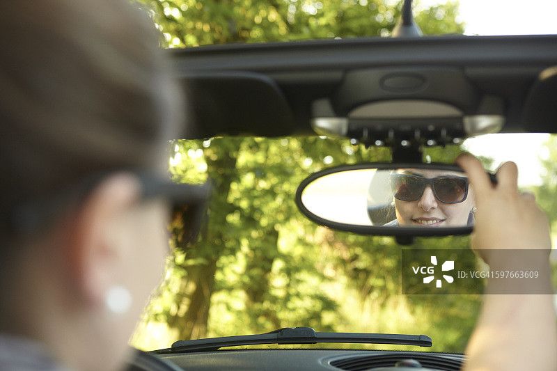 年轻女子在敞篷车里调整后视镜图片素材